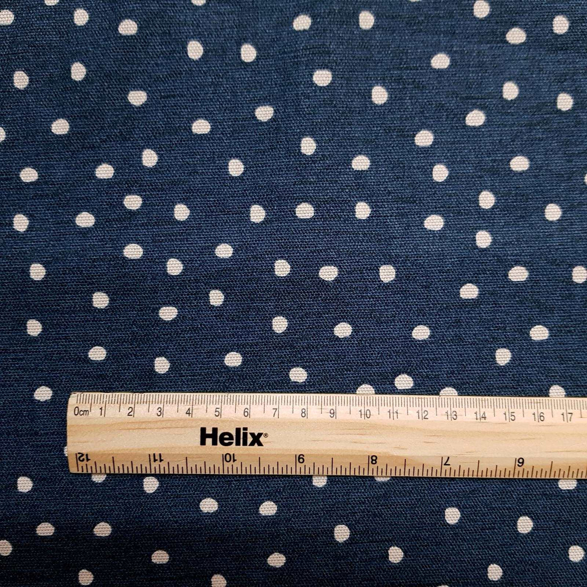 Cotton curtain fabric midnight blue with a spot design and a rule for scale