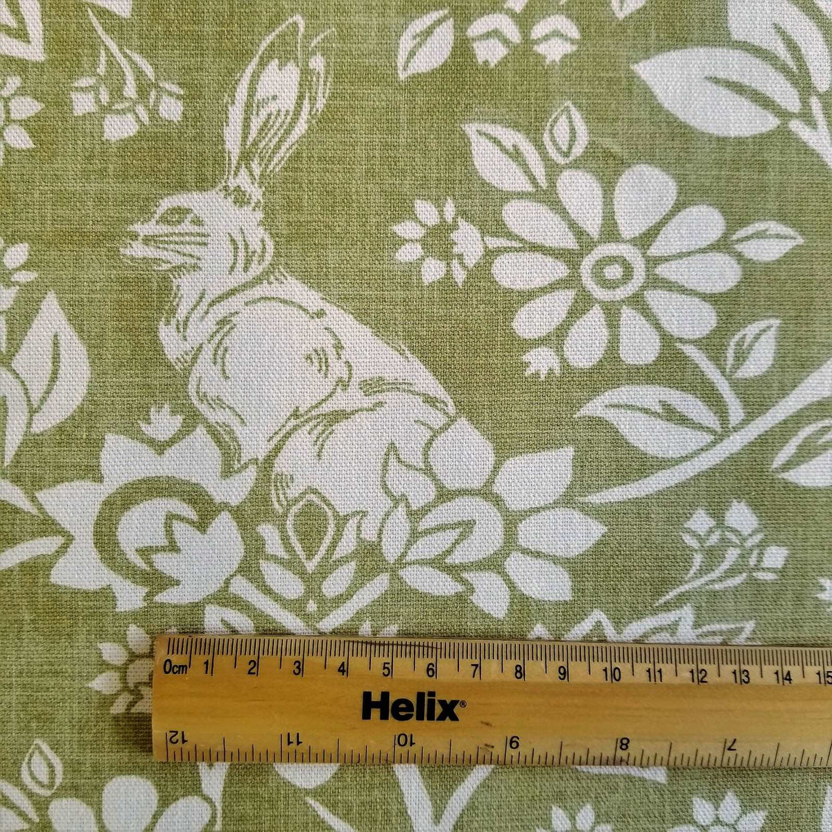 Green curtain fabric with a rule showing size of hares and pheasants design