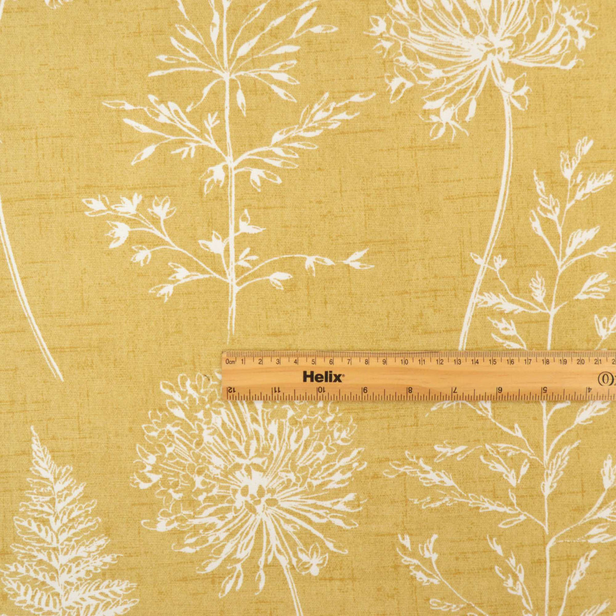 Mustard yellow curtain fabric with a floral pattern and a rule for scale