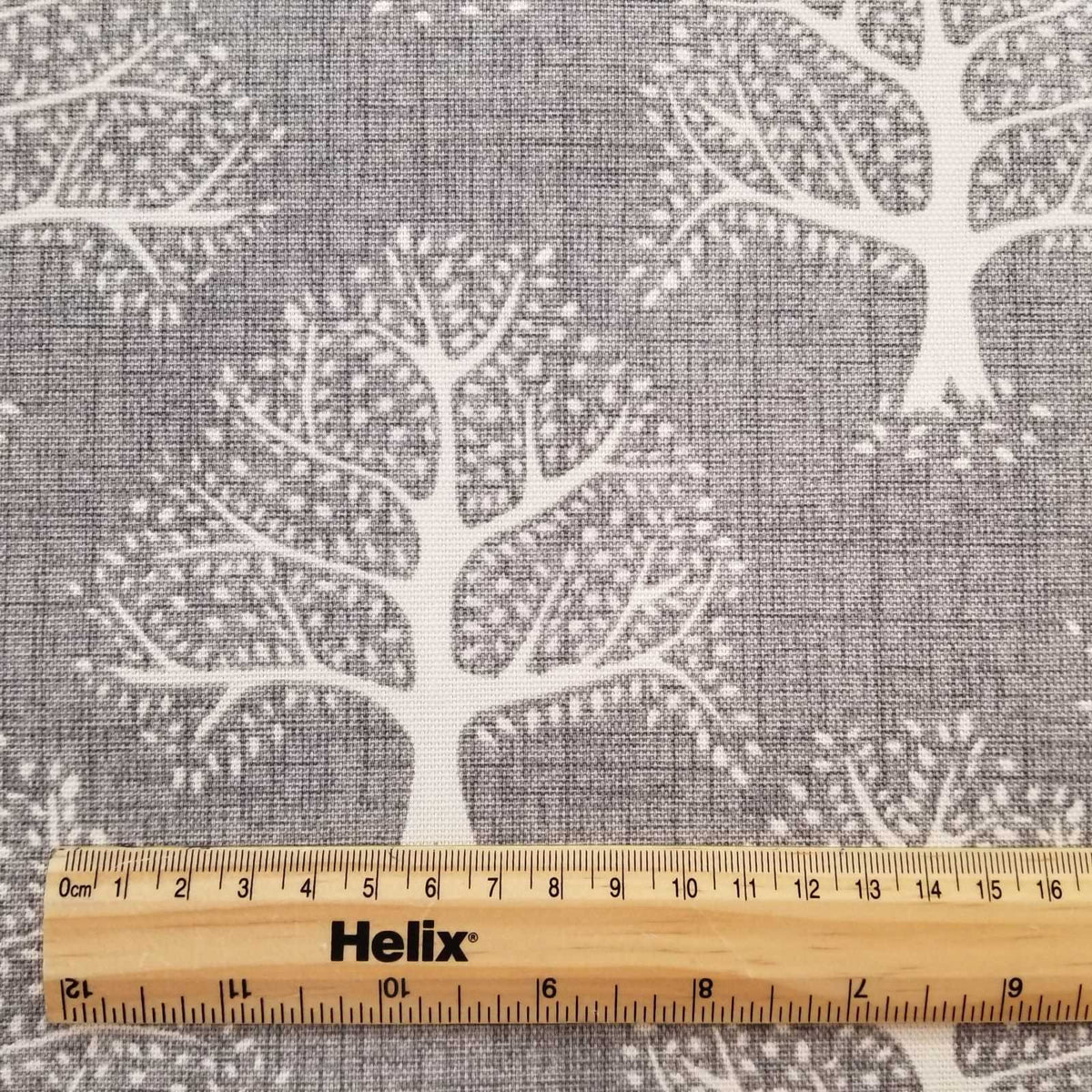 Grey Fabric with a print of oak trees and and a rule for scale