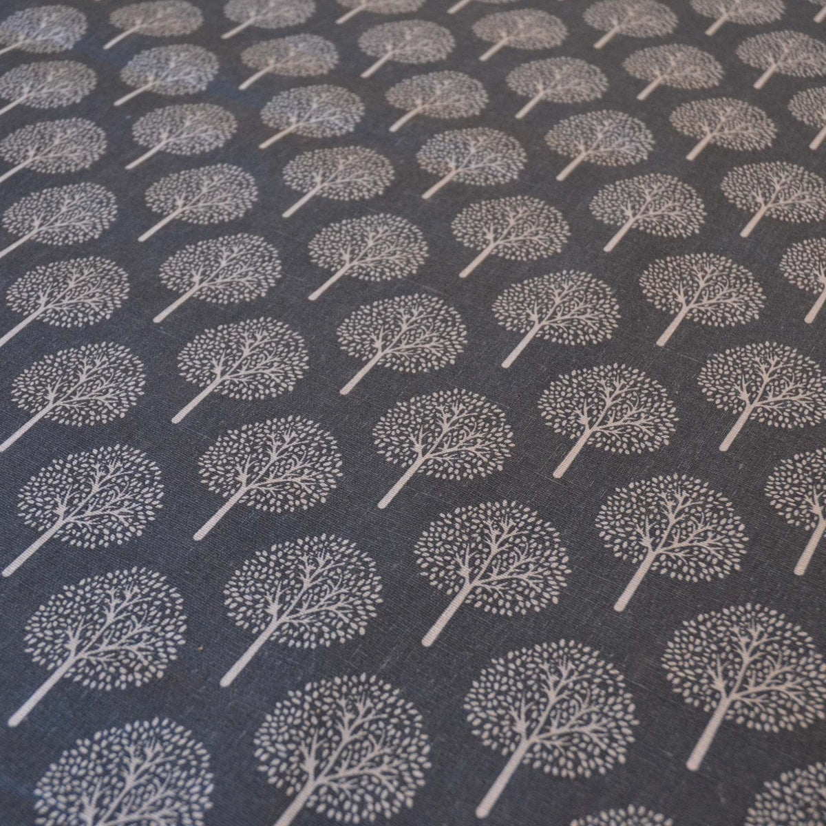 Dark Grey curtain or upholstery fabric with lighter trees, fabric shown at an angle