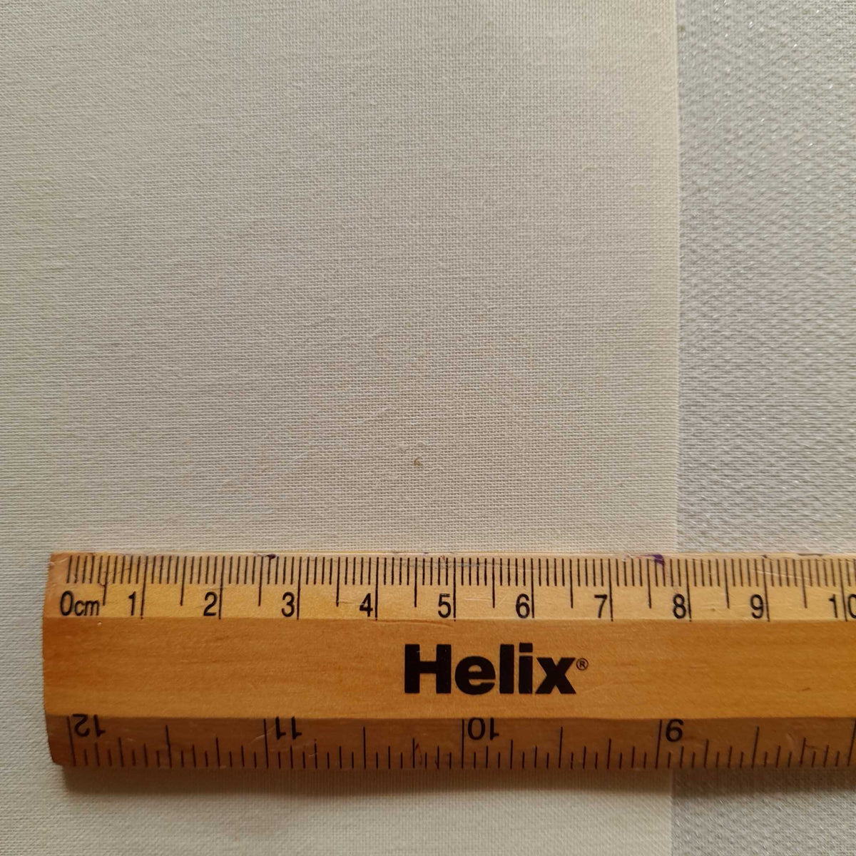 Close view of roller blind backing fabric with rule for scale