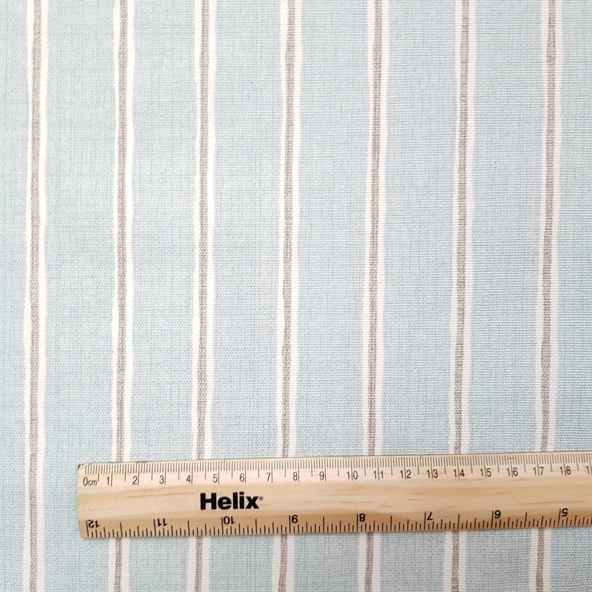 Duck egg colour curtain fabric with a rule showing size of off white and grey stripes