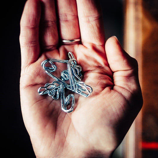 A hand holding silver coloured metal curtain hooks 